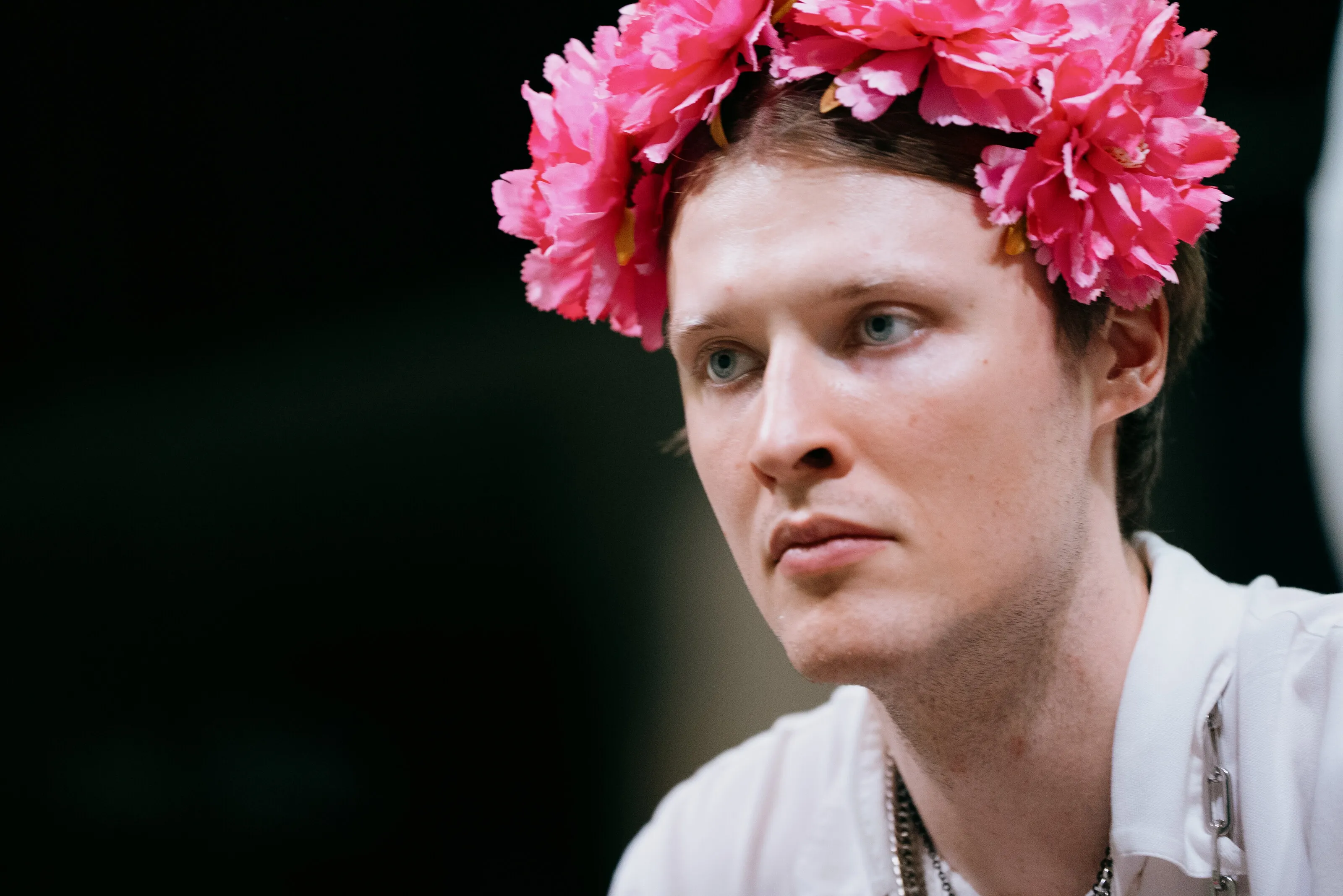 Ein Darsteller mit einem Kranz aus pinken Blüten während der Aufführung.