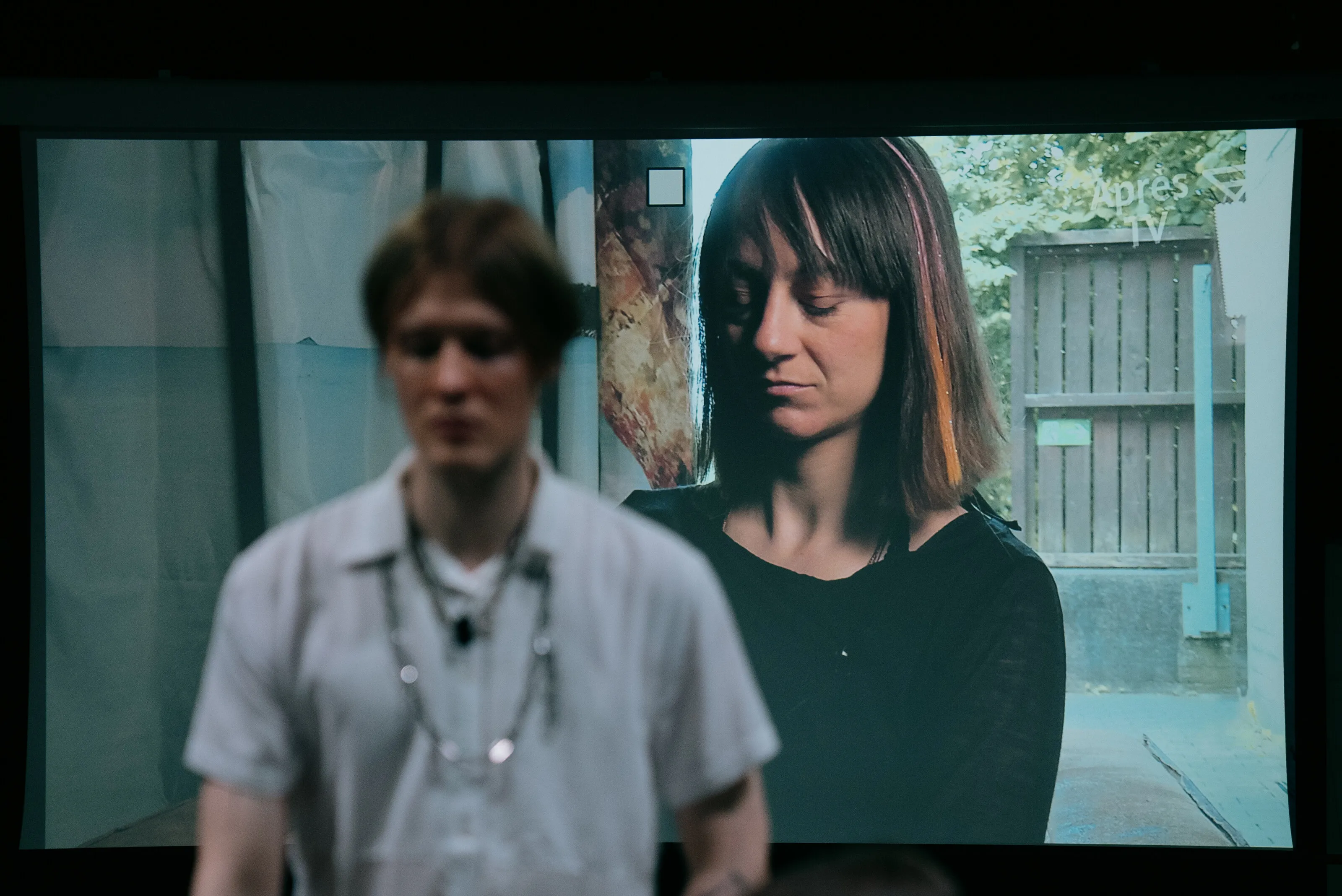Ein Darsteller steht vor der grossflächigen Videoprojektion einer Ensemblekollegin.